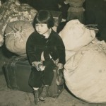 A young Japanese American evacuee waits with the family's luggage before leaving for an assemby center, 1942. Courtesy of the National Archives.