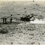 In Italy, two US soldiers guard two surrendering German soldiers near their disabled tank.