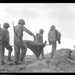 US Marines evacuate a wounded comrade from the front lines on Iwo Jima. (National Archives and Records Administration, 80-G-412493.)